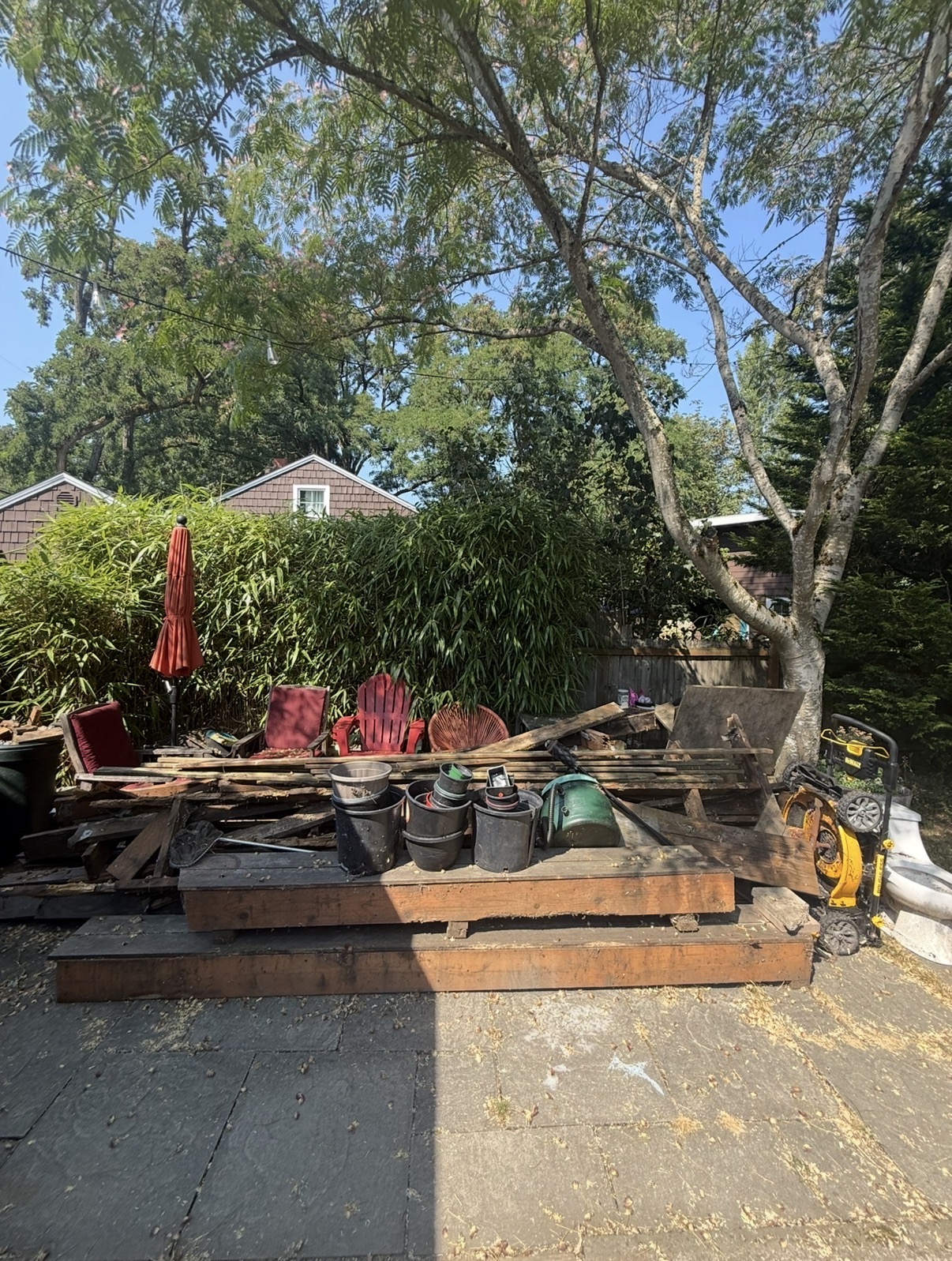 Backyard patio cluttered with old lumber, broken furniture, and debris before hauling